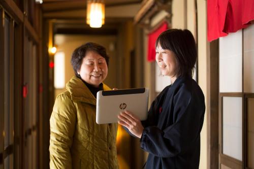 Una donna in piedi accanto a un uomo che tiene un tablet di Super Hydrogen Rich Spa Yado Kanzan a Minakami