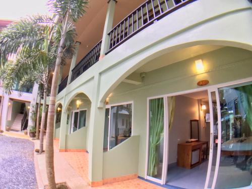 a building with palm trees in front of it at Srichada Hotel Khaolak - SHA Extra Plus in Khao Lak