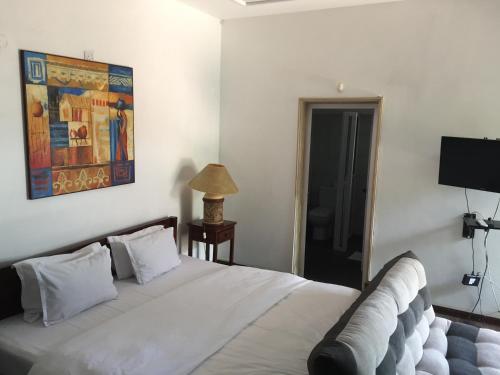 a bedroom with a white bed with a painting on the wall at Villa Alizee in Port Louis
