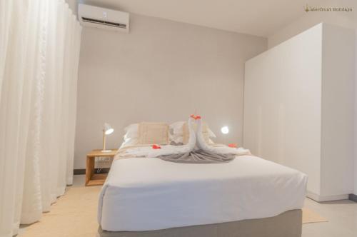 een witte slaapkamer met een wit bed en een tafel bij O'Biches Beachfront Complex - Trou aux Biches in Trou aux Biches