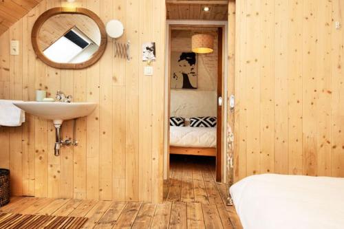 uma casa de banho com um lavatório, uma cama e um espelho. em Vakantiewoning Martha em Veurne