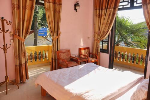 een slaapkamer met een bed, een stoel en een raam bij Thanh Ha Homestay Sapa in Sa Pa