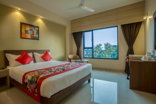 a hotel room with a bed and a large window at Hotel Malisca in Siliguri
