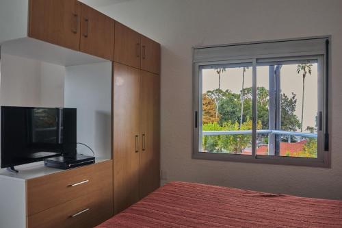 a bedroom with a bed and a tv and a window at Paradise Complejo Turístico in Atlántida