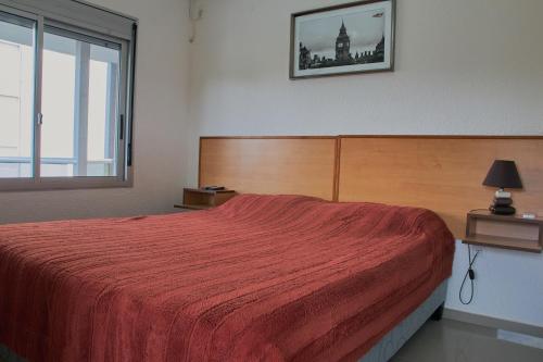 - une chambre avec un lit doté d'un couvre-lit rouge et d'une fenêtre dans l'établissement Paradise Complejo Turístico, à Atlántida