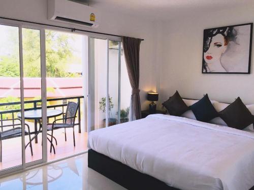 a bedroom with a bed and a balcony with a table at Baba Guest House in Kamala Beach