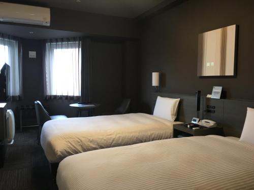 a hotel room with two beds and a telephone at Hotel Route-Inn Grand Tokyo Toyocho in Tokyo