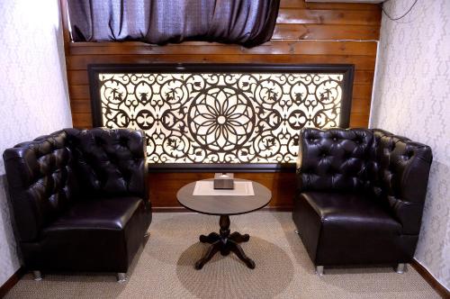 two leather chairs and a table in a room at Pride Hotel in Taraz