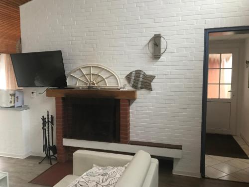 a living room with a white brick fireplace at Gemütlicher Bungalow in Neuharlingersiel