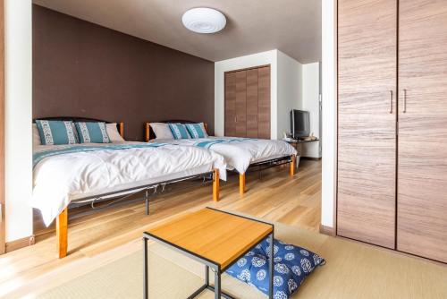 1 dormitorio con 2 camas y mesa en Tino Asuka en Osaka