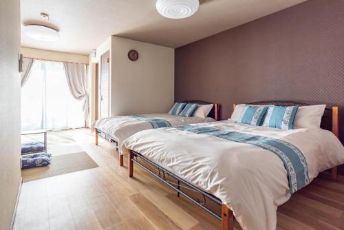 a bedroom with two beds and a window at Tino Asuka in Osaka