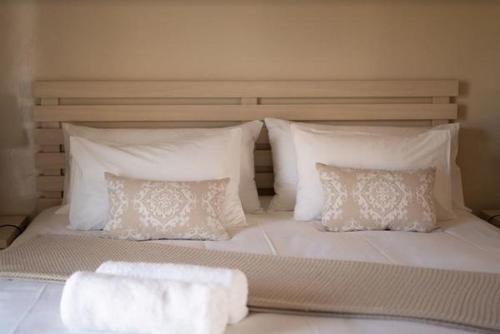 a large white bed with pillows and towels on it at Grand House Lodge And SPA Jeffreys Bay in Jeffreys Bay