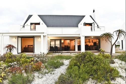 a white house with palm trees in front of it at Hemel op Aarde Villa in Dwarskersbos