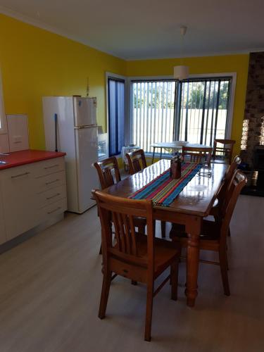 a kitchen with a wooden table with chairs and a refrigerator at Poss' Place in Rocky Cape