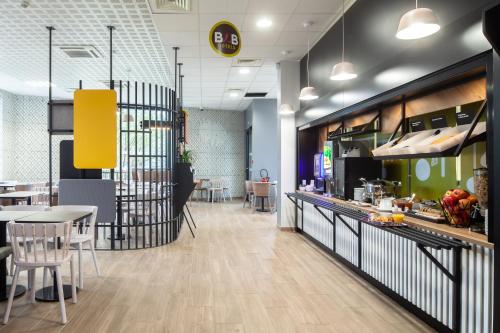 a restaurant with a counter and a table and chairs at B&B HOTEL Paris Gennevilliers Asnières in Gennevilliers