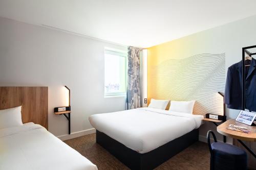a hotel room with two beds and a desk at B&B HOTEL Paris Gennevilliers Asnières in Gennevilliers