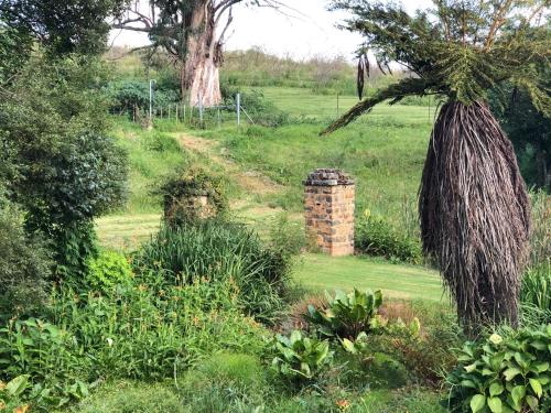 a garden with a palm tree and a brick pillar at Newstead Farm - Country Cottages in Curryʼs Post