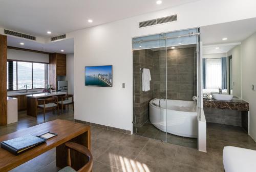 a bathroom with a tub and a sink and a table at Joy Trip Hotel & Spa Nha Trang in Nha Trang
