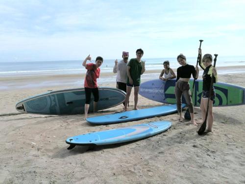a group of people standing on a beach with surfboards at Tree Roots Retreat in Rayong