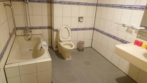 a bathroom with a toilet and a tub and a sink at Kenting City Gate Hotel in Hengchun