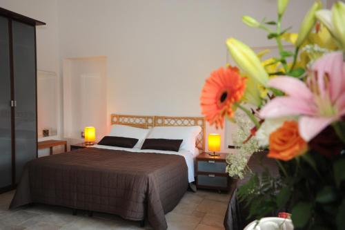 a bedroom with a bed with two lamps and flowers at L'antico Trullo - Masseria Chiancarella in Fasano