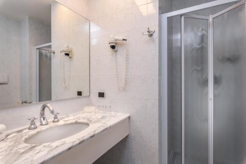 a white bathroom with a sink and a shower at Hotel Polo in Rimini