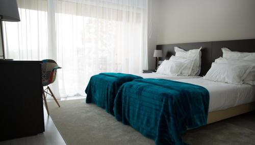 a bedroom with a bed with a blue blanket on it at Casa de Campo Memórias da Comarca in Arganil