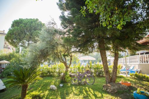a bike parked under two trees in a yard at Halıcı Hotel Marmaris in Marmaris