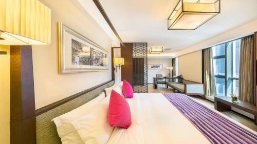 a bedroom with a large white bed with pink pillows at SSAW Boutique Hotel Ningbo CBD - Family Friendly & Business Travel in Ningbo