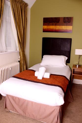 a bedroom with a bed with two towels on it at The Twelve Knights in Port Talbot