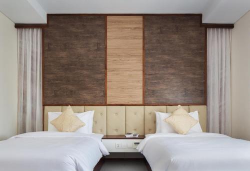 two beds in a hotel room with white sheets at LCS Hotel & Apartment in Phnom Penh