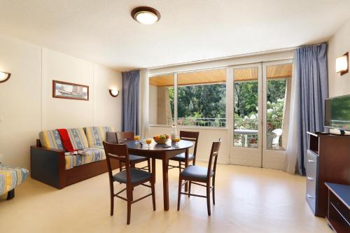 a room with a table and chairs and a bedroom at Vacancéole - Le Domaine de Chames - Pont d'Arc in Vallon-Pont-dʼArc