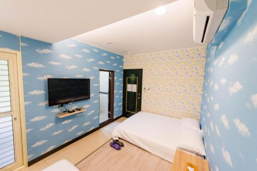 a bedroom with a blue wall with clouds and a tv at ManMan House Ruifang in Ruifang