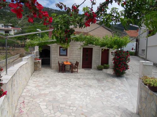 a courtyard of a house with a table and red flowers at Apartments Popaj in Komiža