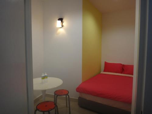 a small bedroom with a red bed and a table at Famosa 2 Stay in Melaka