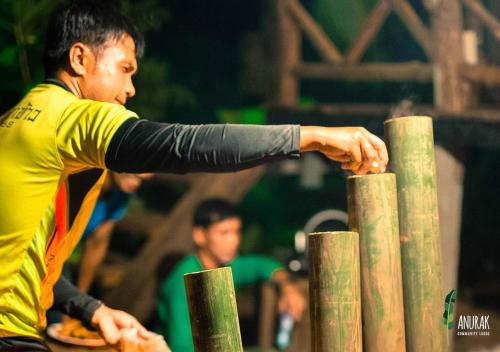 a man is reaching over a wooden fence at Anurak Community Lodge - SHA Plus in Khao Sok