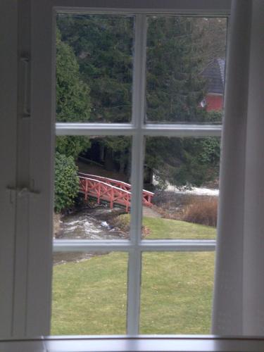 a window view of a red bridge seen through a window at Skarrildhus Sinatur Hotel & Konference in Skarrild