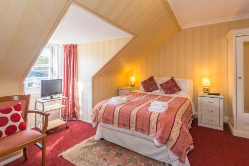 a bedroom with a bed and a tv and a chair at Menzies Guest House in Edinburgh