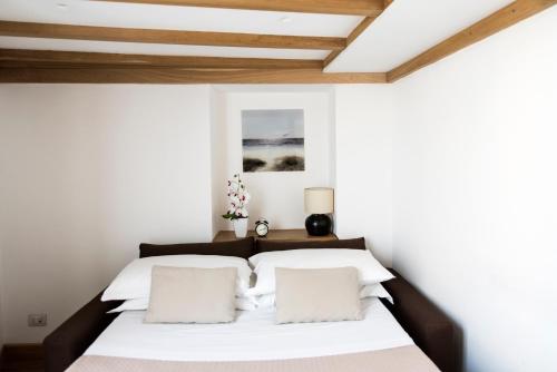 a bedroom with a bed with white sheets and wooden ceilings at Agora Apartments in Sorrento