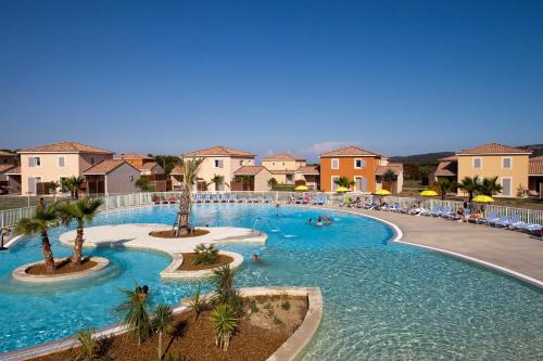 une grande piscine avec des palmiers dans un complexe hôtelier dans l'établissement Le Domaine du Golf*** by Ateya Vacances, à Fabrègues