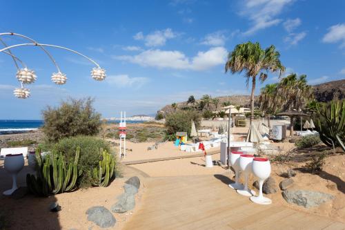 a boardwalk leading to a beach with palm trees at Bungalow Palm Mar with pool and garden in Arona