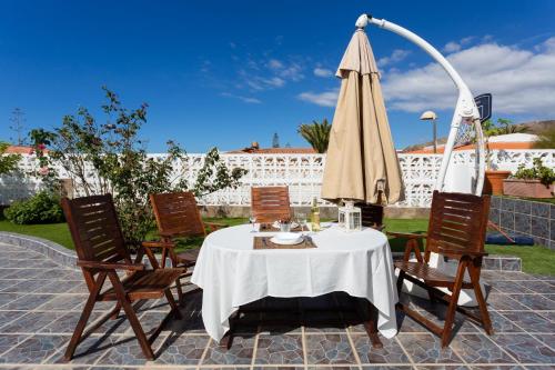 a table with an umbrella and four chairs at Bungalow Palm Mar with pool and garden in Arona