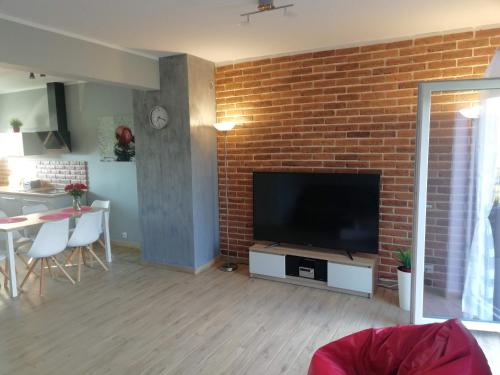 a living room with a brick wall and a flat screen tv at Dofu Domek in Trzęsacz