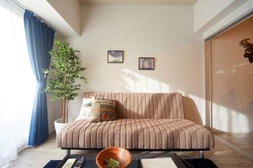 a living room with a couch and a plant at nedoco OSAKA SHINSAIBASHI - formerly FORESTAY Shinsaibashi in Osaka