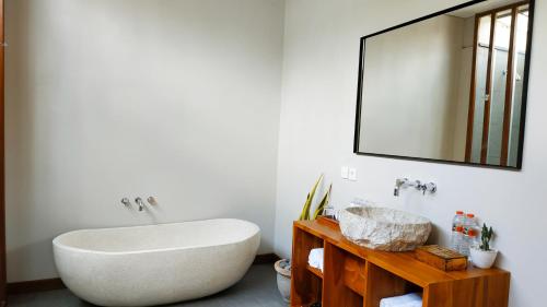 a bathroom with a large white tub and a mirror at Anggira Villa Ubud in Ubud