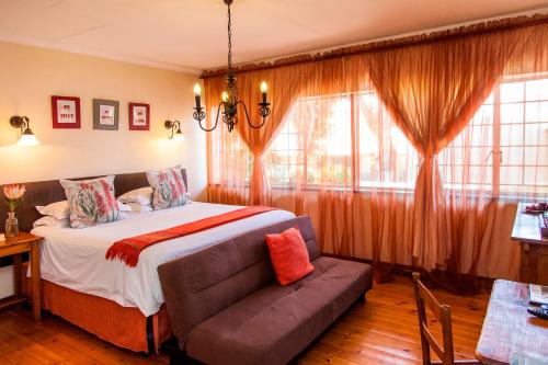 a bedroom with a bed and a couch and windows at 3@Marion Guest House in Pretoria
