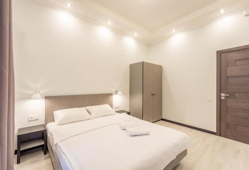 a white bedroom with a large bed and a cabinet at DayFlat Apartments Golden Gate Area in Kyiv