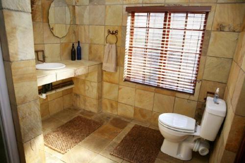 a bathroom with a toilet and a sink and a window at 3@Marion Guest House in Pretoria