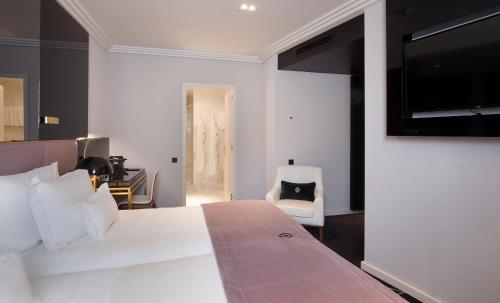 a bedroom with a large white bed and a chair at Altis Avenida Hotel in Lisbon