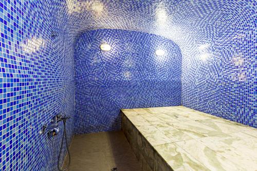 uma casa de banho em azulejos azuis com um chuveiro e um balcão em Renion Residence Hotel em Almaty